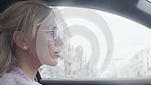 The concept of lifestyle and beauty. Close-up of the charming face of a young blonde driving her car.
