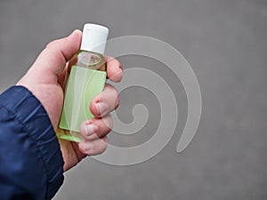 Concept of living in a new reality of coronavirus epidemic hysteria man`s hand holding sanitizer gel bottle outdoors on city