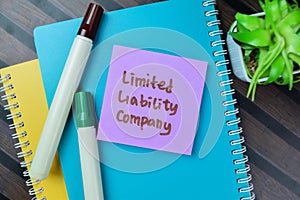 Concept of LLC - Limited Liability Company write on sticky notes isolated on Wooden Table