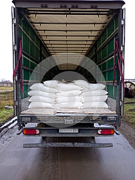 The concept of logistics conveyor delivery. Modern large trailer, with bags of flour. Route of Industrial Warehouses