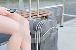 Concept of long-dictance journey or trop. Close up photo of suitcase, woman`s legs and sunglasses