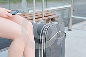 Concept of long-dictance journey or trop. Close up photo of suitcase, woman`s legs and sunglasses photo