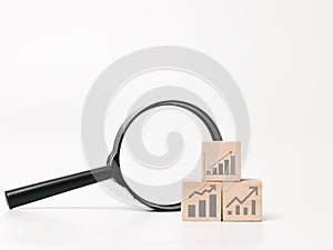 Concept of looking for business profit and revenue on wooden cubes with magnifier.