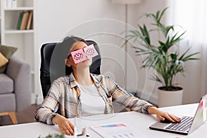 The concept of a lot of work. Tired Indian student girl sleeping with stickers on her eyes while sitting at the table