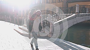 Concept of love. Handsome european man carrying on his back gorgeous asian woman in the streets of Venice. Young hipster