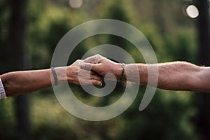 Concept of love and help each other people or relationship - close up of hands touching and holding or helping - green bokeh