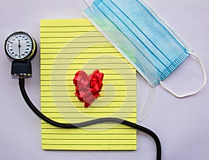 concept love medical blue mask with notepad and manual blood pressure reader and a ribbon heart representing love for doctors