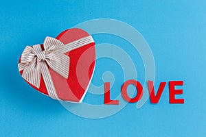 Concept for love stories and for Valentine`s Day. The inscription `Love`, hearts and a box in the form of a heart on a blue backgr