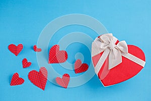 Concept for love stories and for Valentine`s Day. The inscription `Love`, hearts and a box in the form of a heart on a blue backgr