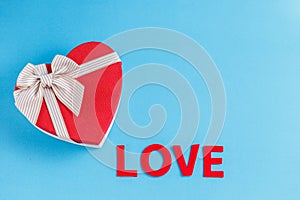 Concept for love stories and for Valentine`s Day. The inscription `Love`, hearts and a box in the form of a heart on a blue backgr