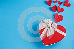 Concept for love stories and for Valentine`s Day. The inscription `Love`, hearts and a box in the form of a heart on a blue backgr