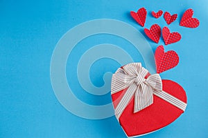 Concept for love stories and for Valentine`s Day. The inscription `Love`, hearts and a box in the form of a heart on a blue backgr