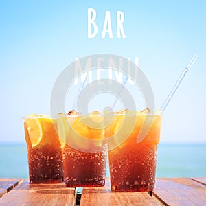 Concept of luxury tropical vacation. Three Cuba Libre cocktails on the pier. Bar menu wording