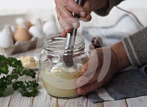 The concept of making homemade mayonnaise from natural healthy ingredients.An elderly woman prepares homemade mayonnaise in a jar