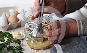 The concept of making homemade mayonnaise from natural healthy ingredients.An elderly woman prepares homemade mayonnaise in a jar