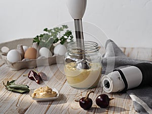 The concept of making mayonnaise at home.A jar with ready-made mayonnaise, vegetable oil, eggs and a blendar for whipping on a