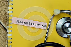 Concept of Malabsorption write on sticky notes with stethoscope isolated on Wooden Table