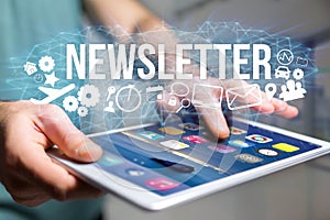 Concept of man holding futuristic interface with newsletter title and multimedia icons flying all around - Internet concept