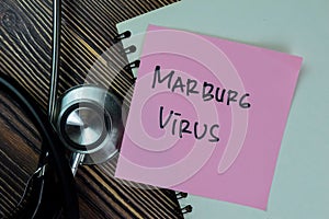 Concept of Marburg Virus write on sticky notes with stethoscope isolated on Wooden Table