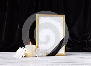 The concept of memory, funerals and condolences. Photo frame with black mourning ribbon, candle and flowers