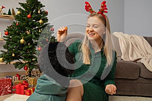 Concept of Merry Christmas, young woman and black Toy poodle in Christmas decorated room