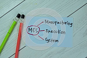 Concept of MES - Manufacturing Execution System write on sticky notes isolated on Wooden Table