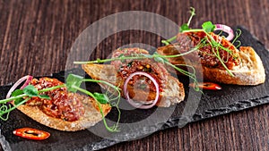 The concept of Mexican cuisine. Beef tartare with parsley, French mustard beans on baguette croutons. A dish in the restaurant