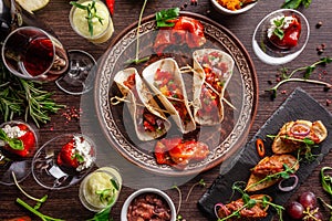 The concept of Mexican cuisine. Mexican food and snacks on a wooden table. Taco, sorbet, tartar, glass and bottle of red wine. photo