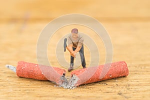 Concept miniature people destroying a Firecracker