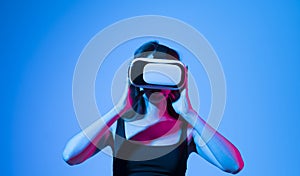Concept of modern gadgets and technologies. Future technology concept. Portrait of young woman in VR-glasses in neon