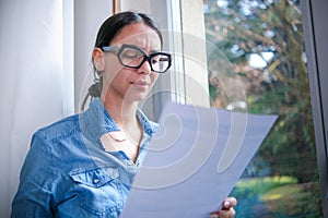 Concept of money problems. Woman's worried expression and the letter in her hand suggest a financial crisis