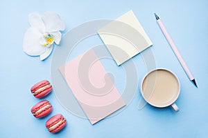 Concept morning Breakfast. Cup of coffee, macaroon cookies and notepad on blue pastel background. Flat lay style
