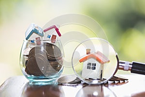 Concept of a mortgage, a coin, a model of a house and a magnifying glass, house and money. magnifying glass and coins,