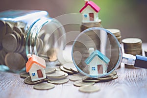 Concept of a mortgage, a coin, a model of a house and a magnifying glass, house and money. magnifying glass and coins,