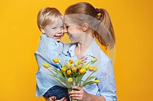 Concept of mother`s day. mom and baby son with flower on colored