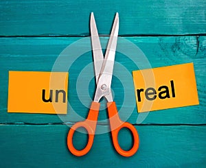 Concept of motivation. the inscription `un real` and scissors between them. goal achievement, potential overcoming. photo