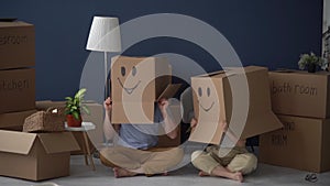 Concept of moving to a new apartment and a mortgage. Unrecognizable couple, husband and wife wearing carton boxes on