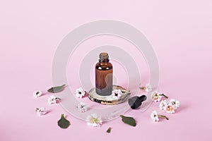 Concept of natural cosmetics for face, body and hair care on a pink background. Glass bottle with liquid on a pink background on a