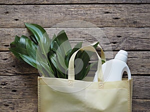 The concept of a natural eco-friendly laundry detergent for the bathroom. Green leaves of a tropical plant in a yellow cotton bag