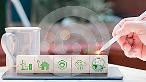 Concept of net zero and carbon neutrality. Hand places wooden cubes with the netzero icons for waste recycling, green production, photo