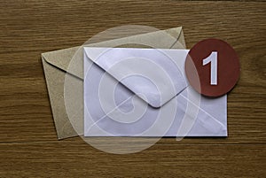 Concept of new email reminder or message alert. A white envelope with a red symbol of notification on a wooden background