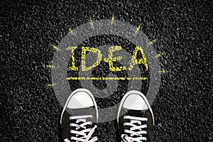 Concept of new ideas. Sneakers on an asphalt road. Glowing light bulb. Top view. Business. Creation.