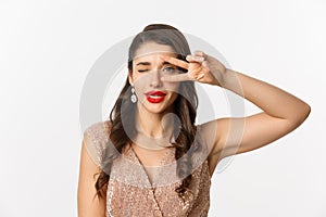 Concept of New Year celebration and winter holidays. Close-up of glamour woman in party dress, red lips, showing peace