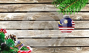 Concept of New Year and Christmas, on a wooden background, Christmas tree branches and a Christmas toy with the flag of Malasia photo