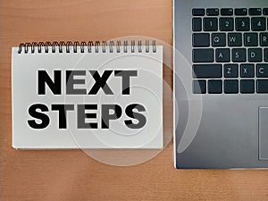 The concept of the next step for career growth in the company. Word - next steps, on notepad with laptop