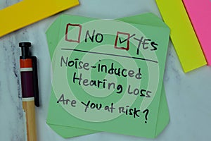 Concept of Noise-Induced Hearing Loss, are you at risk? write on sticky notes isolated on Wooden Table