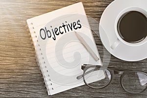 Concept Objectives message on notebook with glasses, pencil and photo