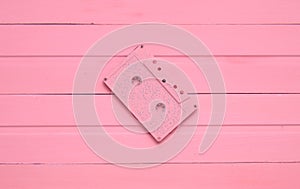 The concept of obsolete audio technology. Retro audio cassette on a pink pastel wooden background. Trend of minimalism.