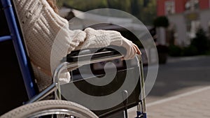 Concept ofparalysis, disability, help and support. Man put his hand on hand of disabled woman on wheelchair, close up