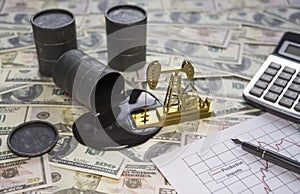 The concept of the oil business. Barrels of oil are worth a dollar money banknote, a gold drilling pump, a calculator